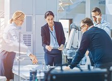 a group of four researchers or engineers around a table are thinking about a problem