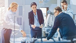 a group of four researchers or engineers around a table are thinking about a problem